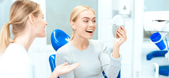 a young woman assessing the results of her cosmetic dentistry