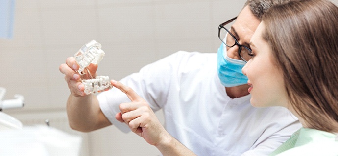 dentist showing a dental implant model to a patient