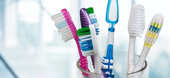 Six toothbrushes sitting in a clear glass