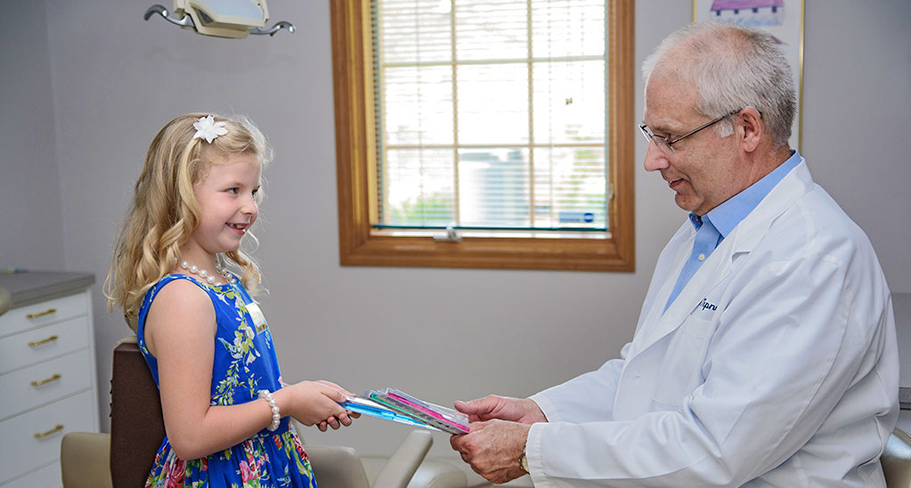 Indianapolis dentist giving a little girl a toothbrush