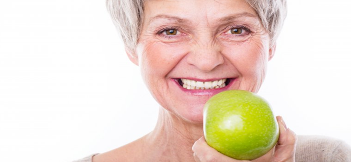 woman smiling holidng a green apple