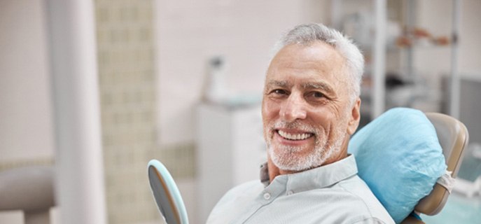 Male dental patient sitting in dental chair with mirror