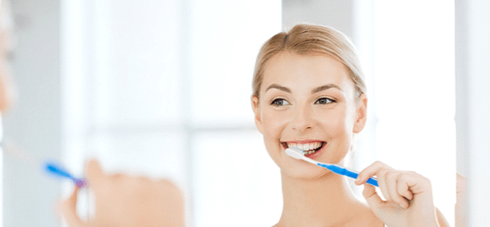 woman brushing after teeth whitening in Indianapolis