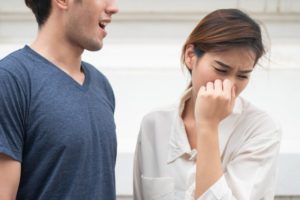 Unhappy woman turning away from man’s bad breath