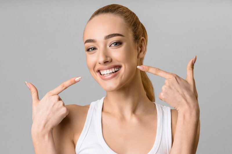 Woman pointing out her white, beaming smile