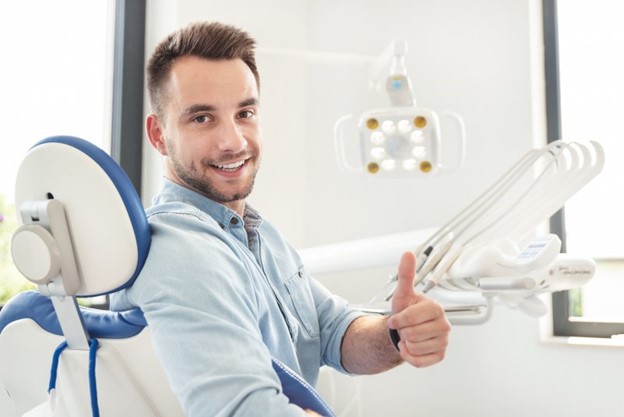 Man giving a thumb’s up during his dental checkup.